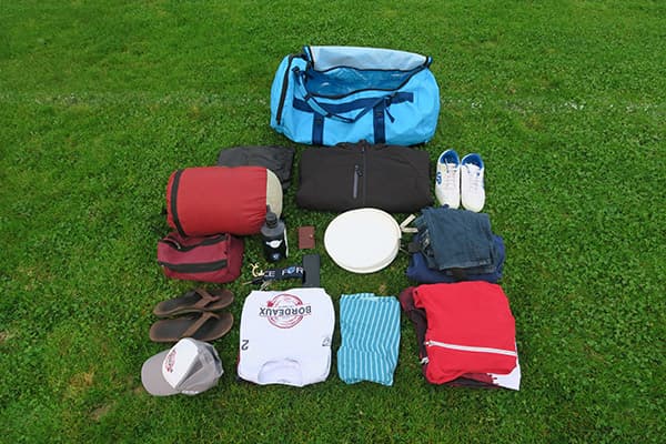 lichtblauwe tas en kleren netjes gerangschikt op gras
