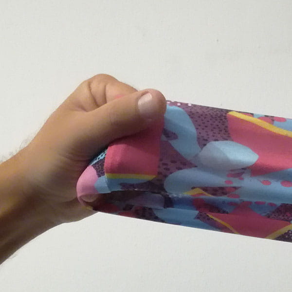 main étirant un tissu rose et bleu clair