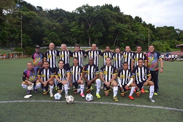 football team loyola wearing black and yellow sublimated jerseys posing on grass field