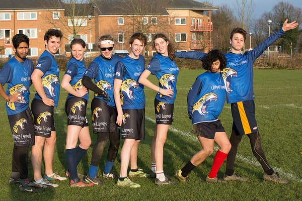 sport players lining up on grass field wearing black shorts and blue jerseys
