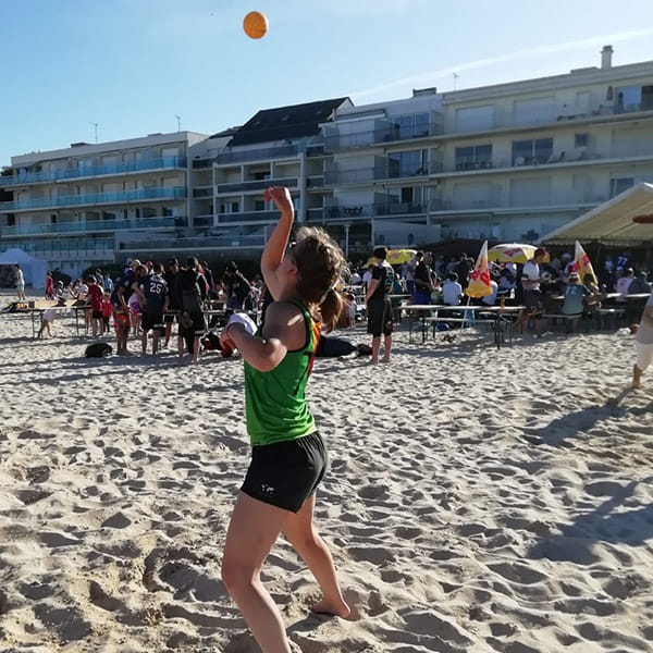 side view of woman on beach playing spikeball