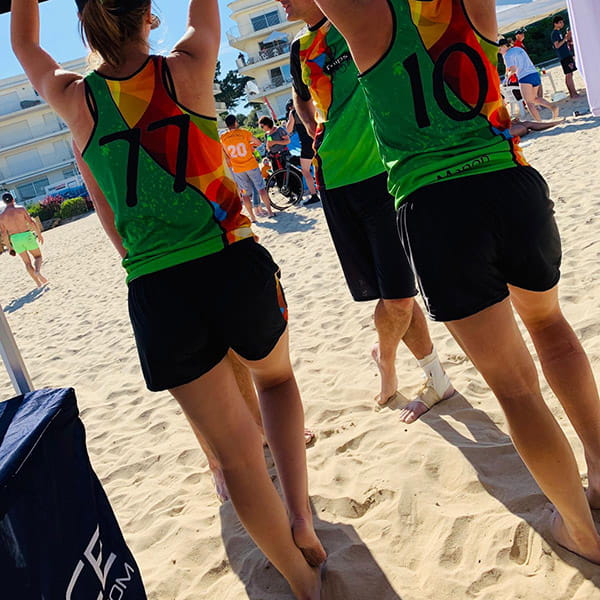 rear view of women on beach under a tent wearing colorful jerseys and short black shorts